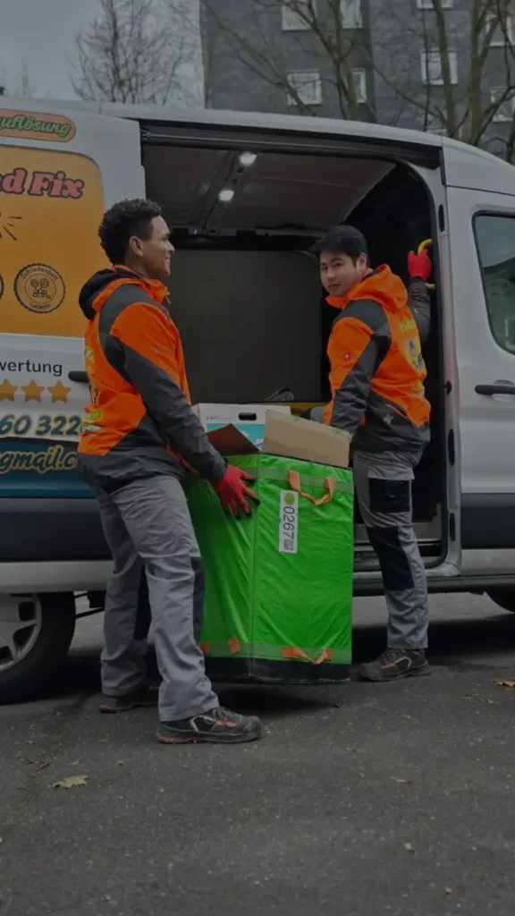 Professionelle Kellerentrümpelung in Aachen: Mitarbeiter von Jung und Fix beladen den Firmentransporter mit einem großen, gefüllten Sack.